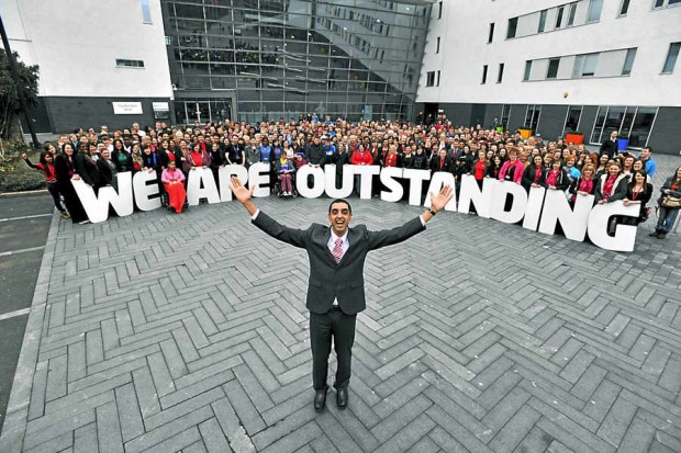 Walsall students standing behind a sign saying 'We are outstanding'